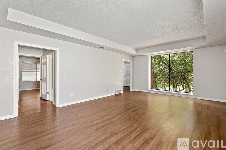 A spacious room with wooden flooring and a large window.