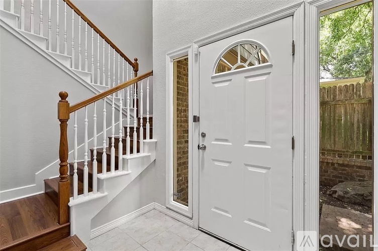 A white door with a glass window is open to a backyard.