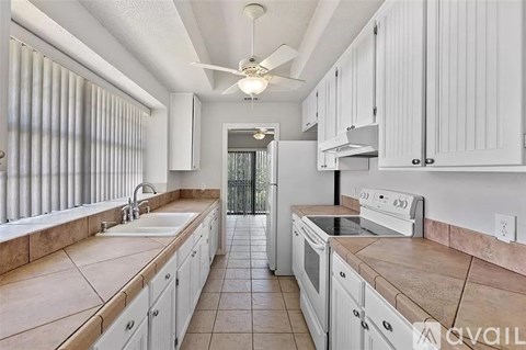 A kitchen with white cabinets and a tiled floor.