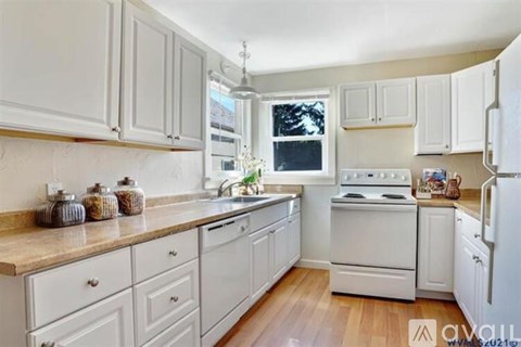 A kitchen with white cabinets and appliances.