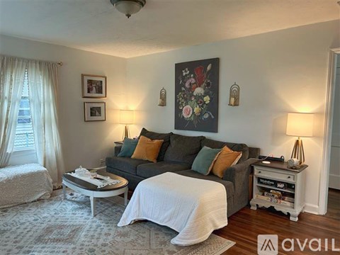 A living room with a grey couch, a coffee table, and a large painting on the wall.