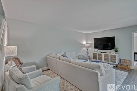 A living room with a grey couch and a television on a cabinet.