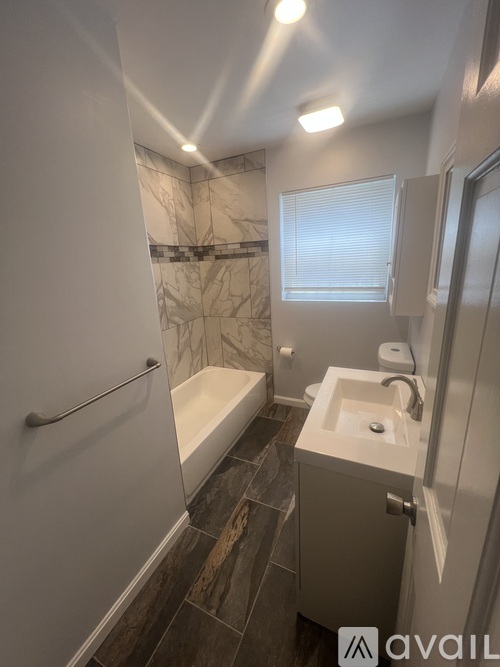 A bathroom with a marble tile shower and a white sink.