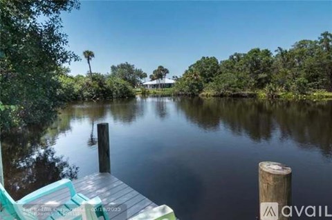 A serene lake with a dock and a house in the distance.