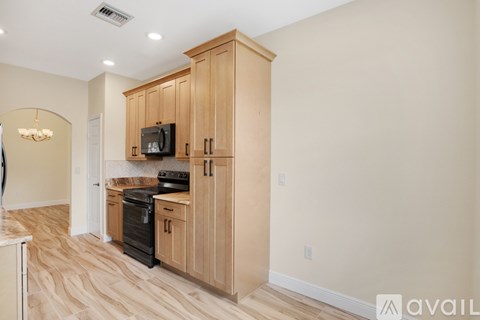 A kitchen with wooden cabinets and a black stove top oven.