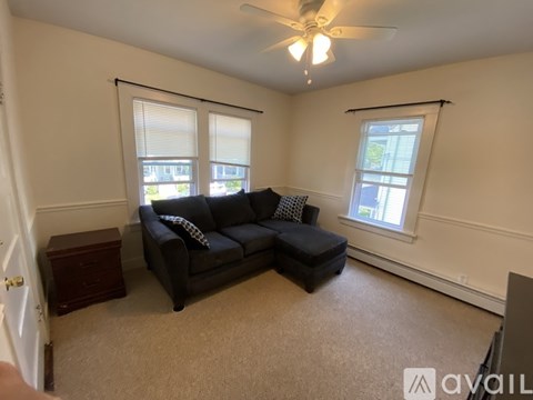 A living room with a black couch and a ceiling fan.