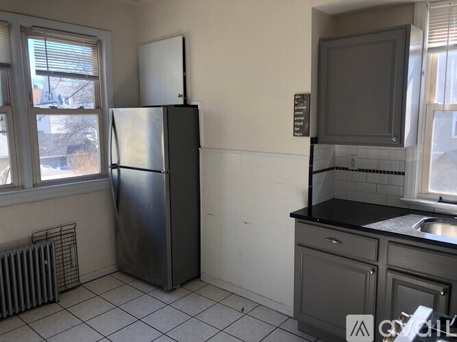 A kitchen with a black fridge and a black counter top.