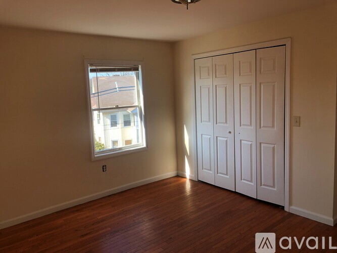 A room with a white door and a window with a view of a building outside.