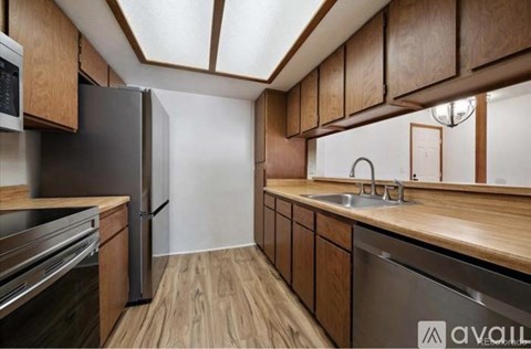 A kitchen with wooden cabinets and a black refrigerator.