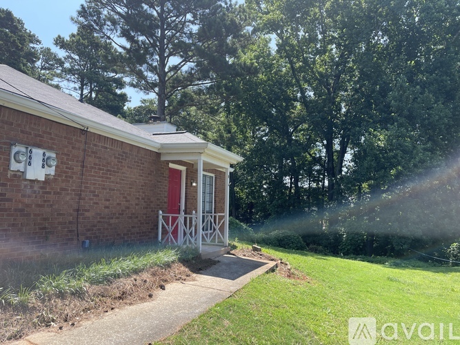 A small brick house with a red door and a porch.