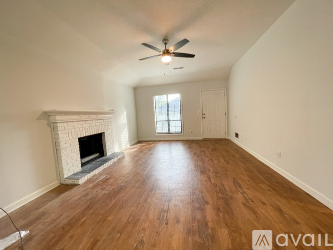 A spacious room with a fireplace and wooden floors.