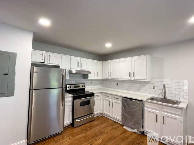 A kitchen with a stainless steel refrigerator and white cabinets.