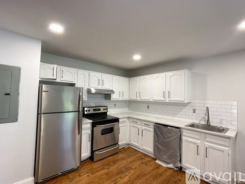 A kitchen with a stainless steel refrigerator and white cabinets.