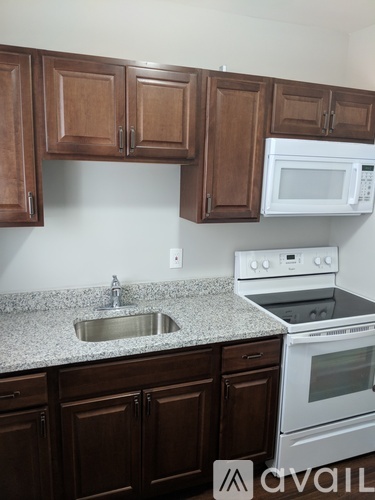 A kitchen with brown cabinets and a white stove.