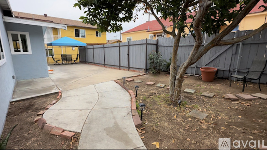 A backyard with a concrete patio and a tree.