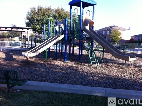 A playground with a blue and green slide and a green bench.