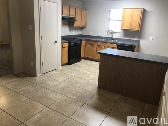 A kitchen with a black dishwasher and wooden cabinets.