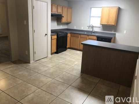 A kitchen with a black dishwasher and wooden cabinets.