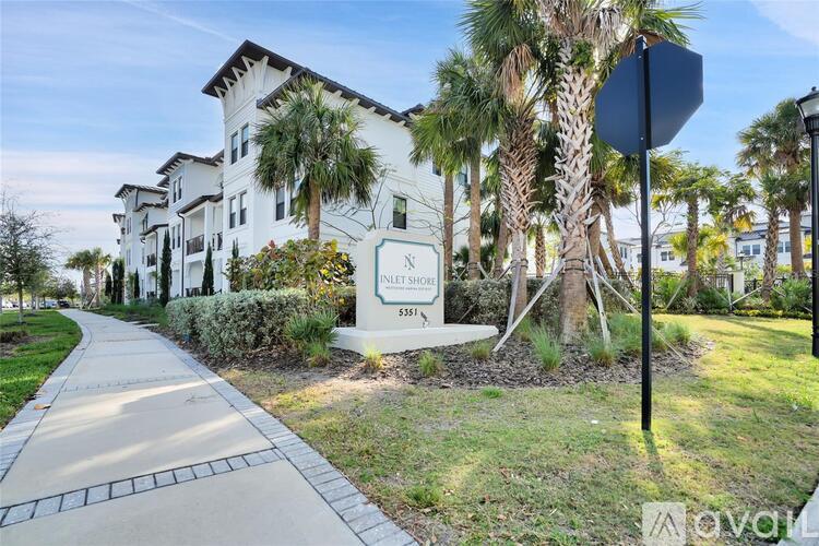 A sign for the Innsbrook apartments is in front of a building with a sidewalk and palm trees.