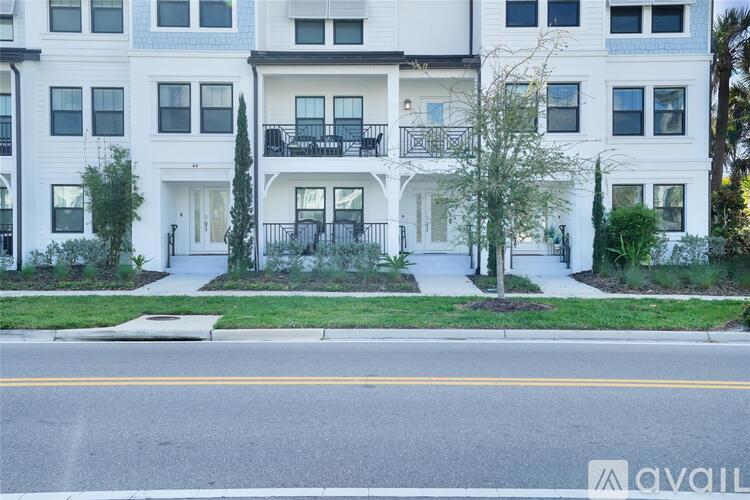 A white apartment building with a balcony on the second floor.