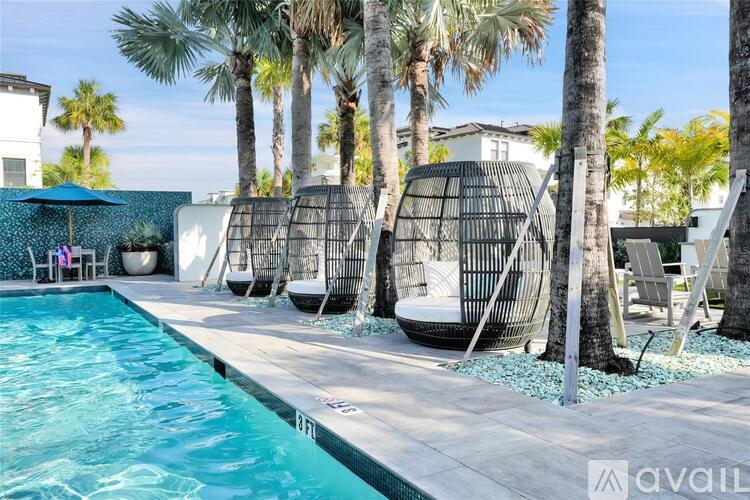A pool surrounded by palm trees and lounge chairs.