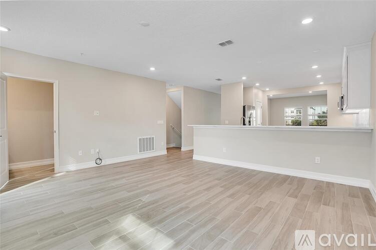 A spacious room with light wood flooring and white walls.