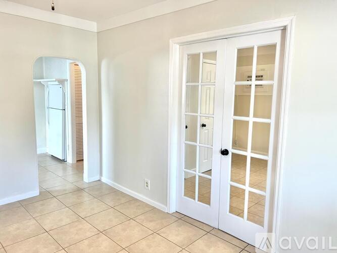 A white door with glass panels is in the center of a room with a tiled floor.