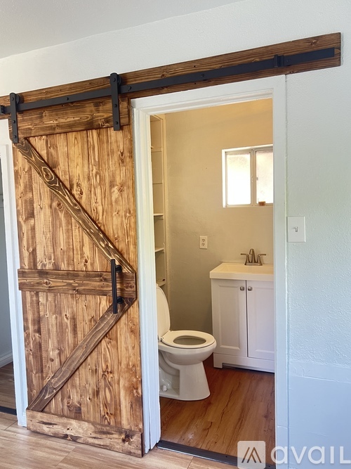 A white toilet is in a small bathroom with a wooden door.