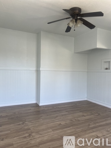 A room with a ceiling fan and wooden flooring.