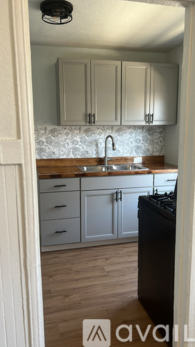 A kitchen with a black dishwasher and wooden floors.