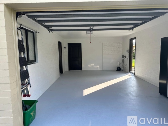 A spacious garage with a green bin and a white wall.