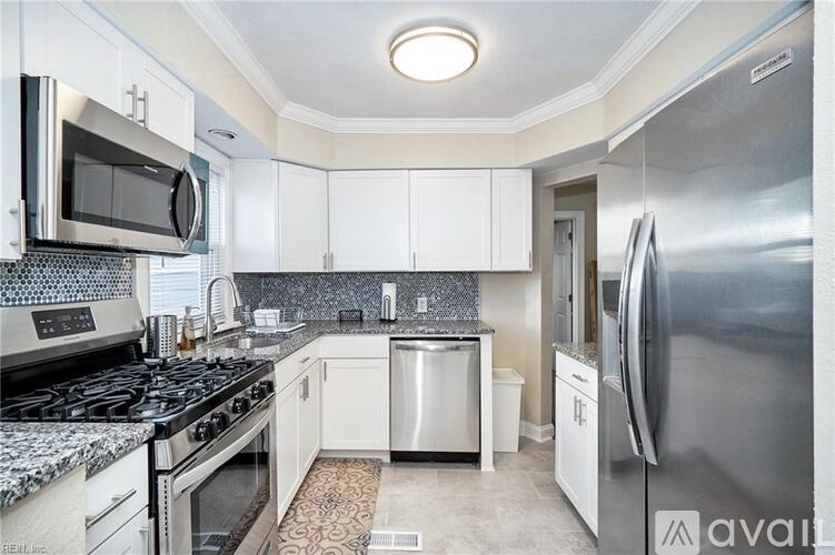 A kitchen with white cabinets and a stainless steel refrigerator.