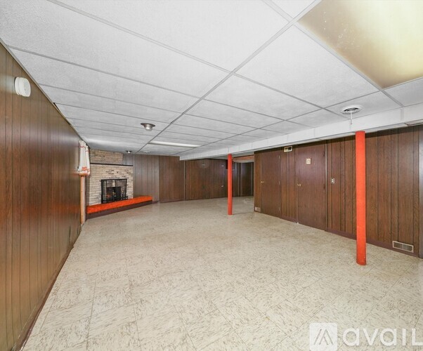 A spacious room with wooden walls and a fireplace.