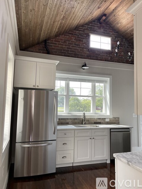 A kitchen with a stainless steel refrigerator and wooden ceiling.