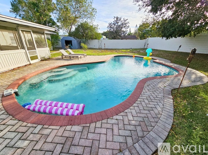 A small pool with a red brick border and a yellow inflatable pool float.