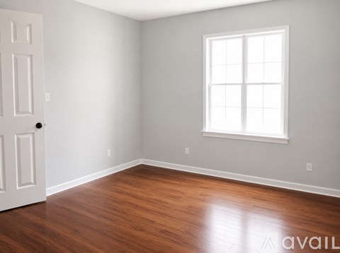 A room with a white door and a window with white blinds.