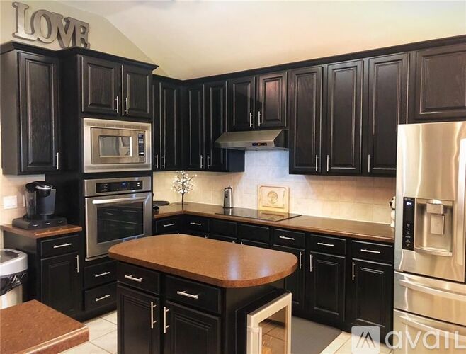 A kitchen with black cabinets and a wooden island.