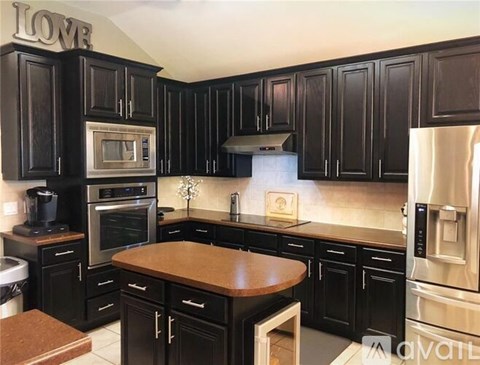A kitchen with black cabinets and a wooden island.