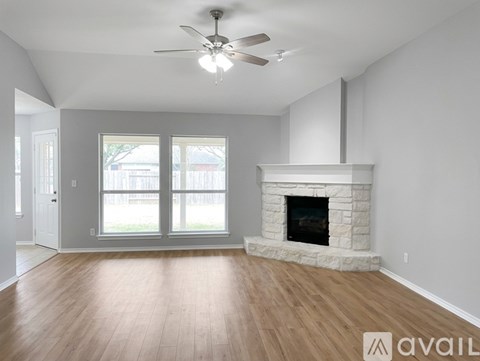 A spacious living room with a fireplace and a ceiling fan.