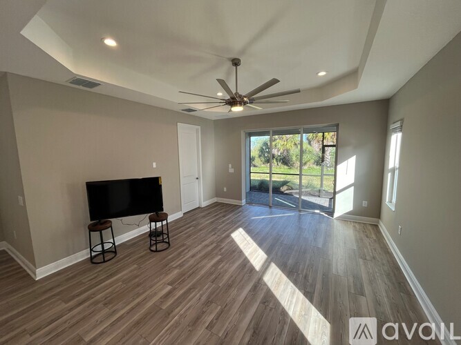 A spacious room with a television and a sliding glass door leading to a patio.