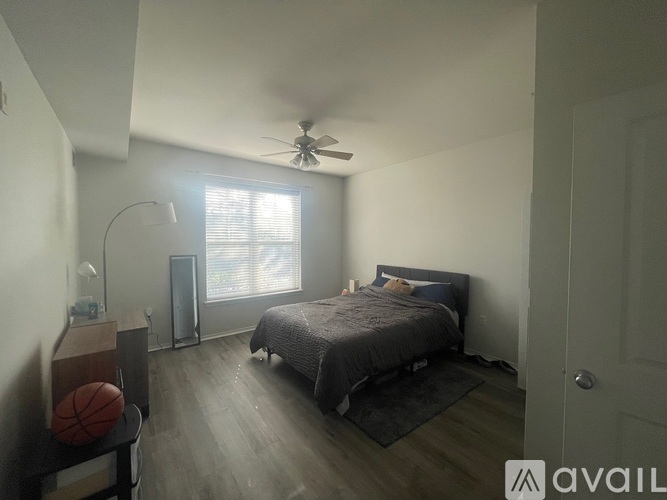 A bedroom with a bed, a ceiling fan, and a basketball on a shelf.
