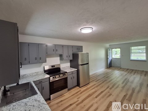 A kitchen with wooden floors and a stainless steel refrigerator.