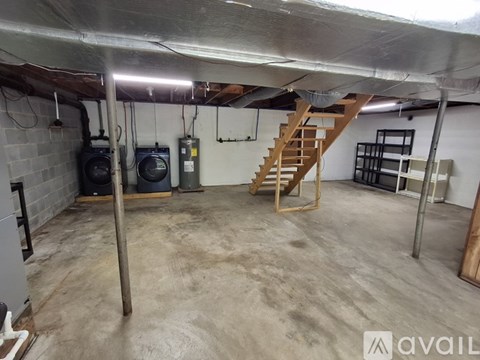 A spacious basement with a staircase, a concrete floor, and a white ceiling.