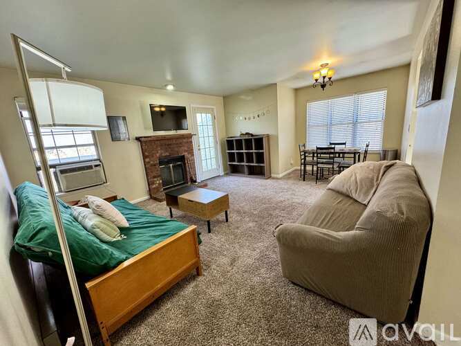 A bedroom with a bed, chair, and fireplace.