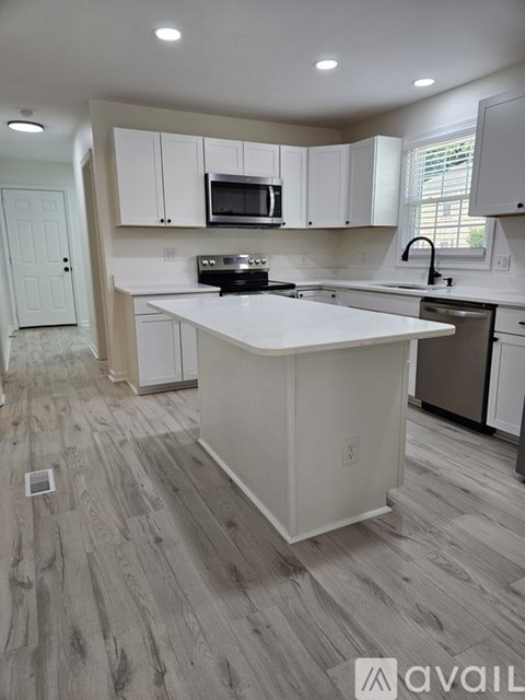 A kitchen with white cabinets and a wooden floor.