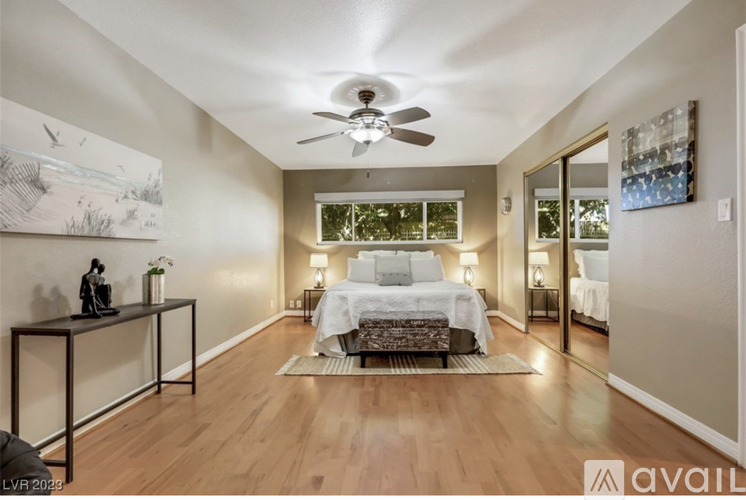 A bedroom with a bed, a table, and a ceiling fan.