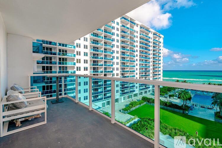 A balcony with a view of the ocean and a building in the background.