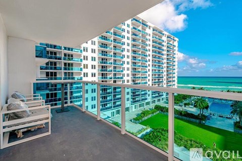 A balcony with a view of the ocean and a building in the background.