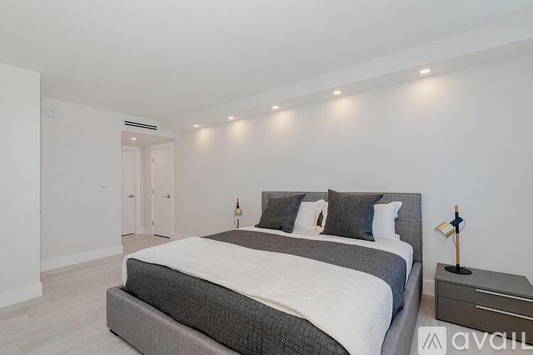 A bedroom with a large bed and a nightstand with a lamp on it.