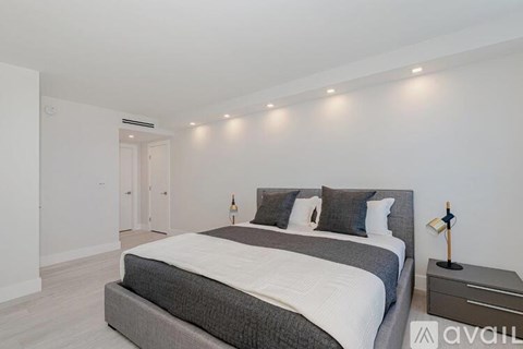 A bedroom with a large bed and a nightstand with a lamp on it.